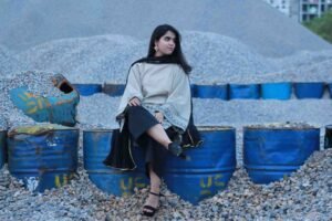 wearing a beige and black patterned 3-piece lawn suit with a black dupatta and wide-leg trousers.