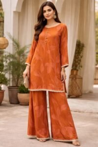 Saffron Glow Suite, a stunning 3-piece vibrant orange lawn suit featuring an exquisite tailored shirt, matching trousers, and a sheer, radiant shafoon dupatta with a regal drape.